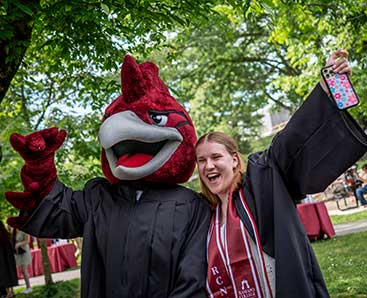 student and a mascot at commencement