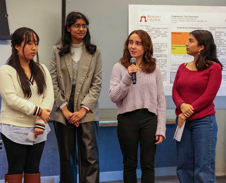 four students talking one holding a microphone